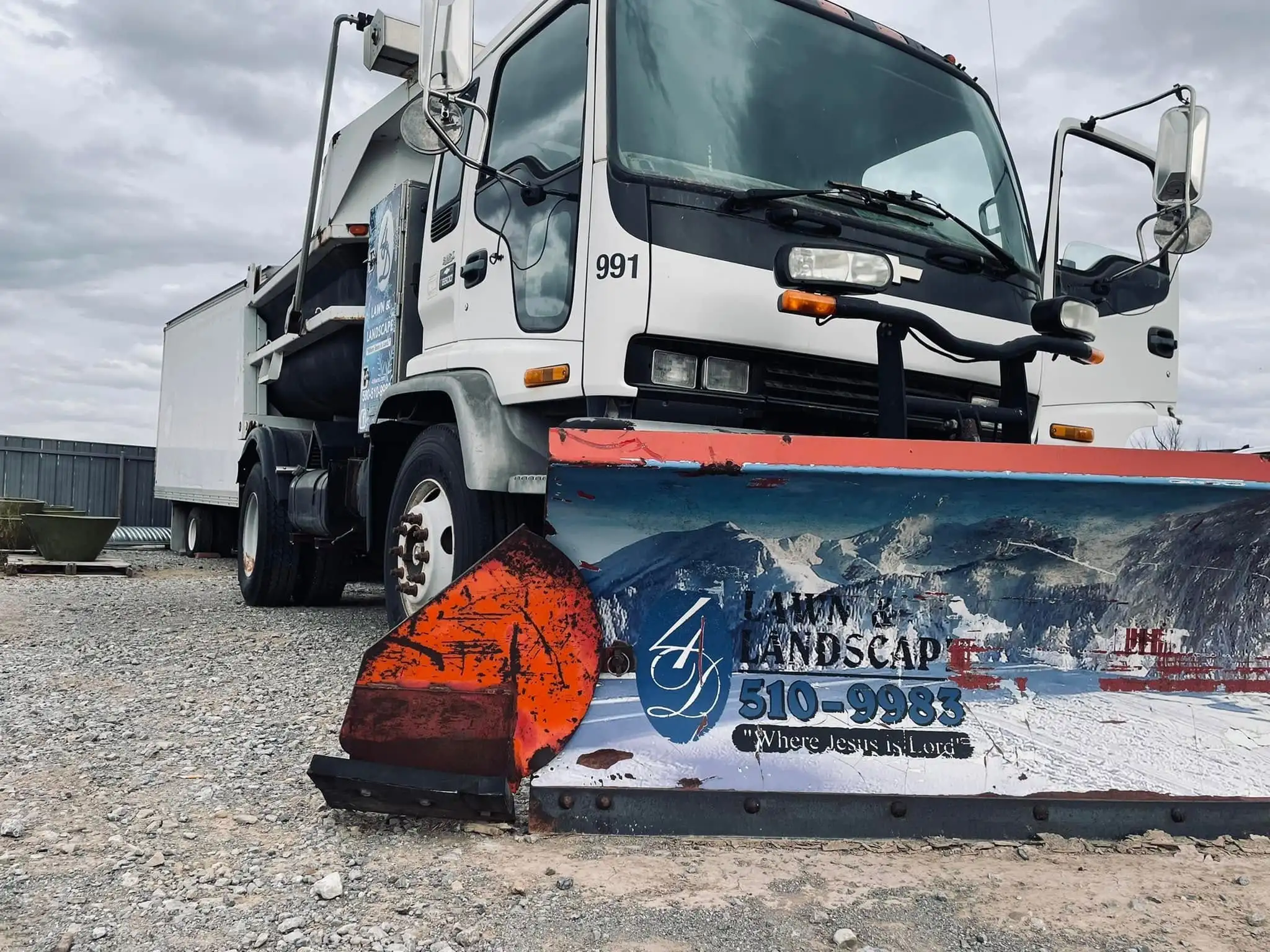 White 4-D snow plow truck, number 991, with a red plow blade showing the 4-D logo, phone number and the words Where Jesus is Lord