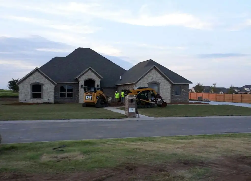 New home with a skid steer grading the front yard before landscaping