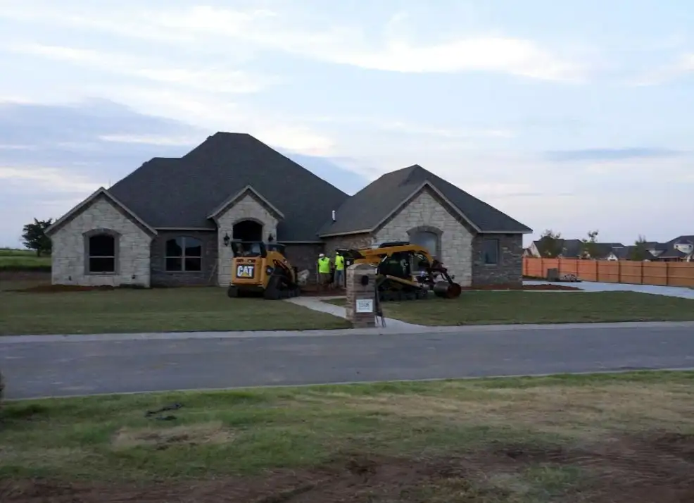 New home with a skid steer grading the front yard before landscaping