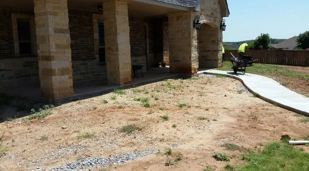 Stone porch and prepared soil with a new walkway and crew at work