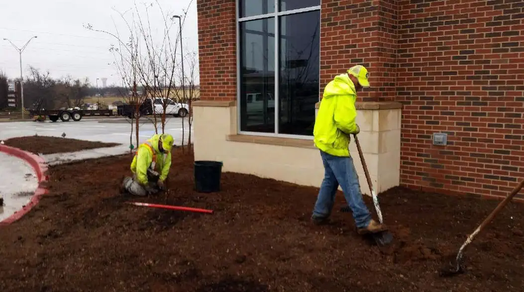 Crew members edging and preparing a landscape bed at a commercial building