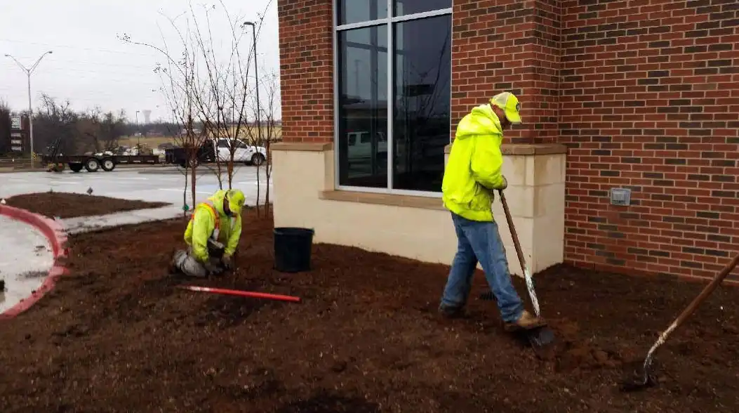 Crew members edging and preparing a landscape bed at a commercial building