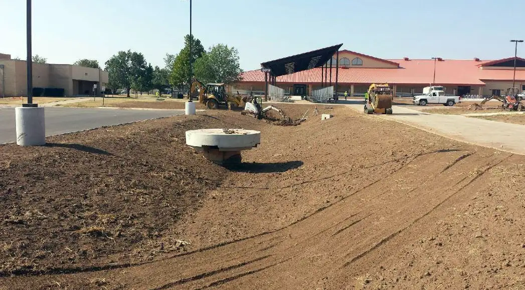 Commercial site grading with curved seating wall and young trees