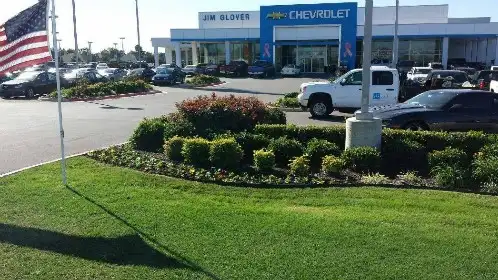 Green, even turf and shrub beds at a commercial property with a flag