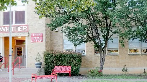 Building entrance before landscaping, with a bare strip beside the walkway