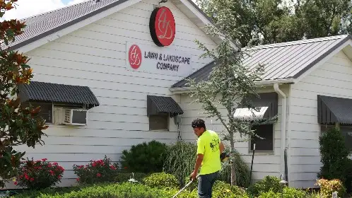 Crew member working at the front of a white office building with fresh landscape beds