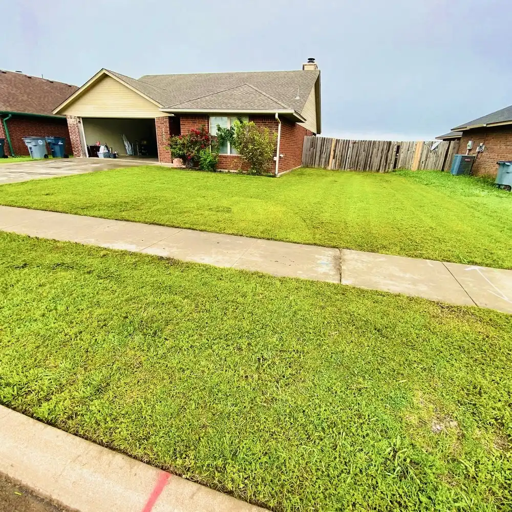 Freshly mowed front lawn with mowing stripes in front of a brick house with an attached garage